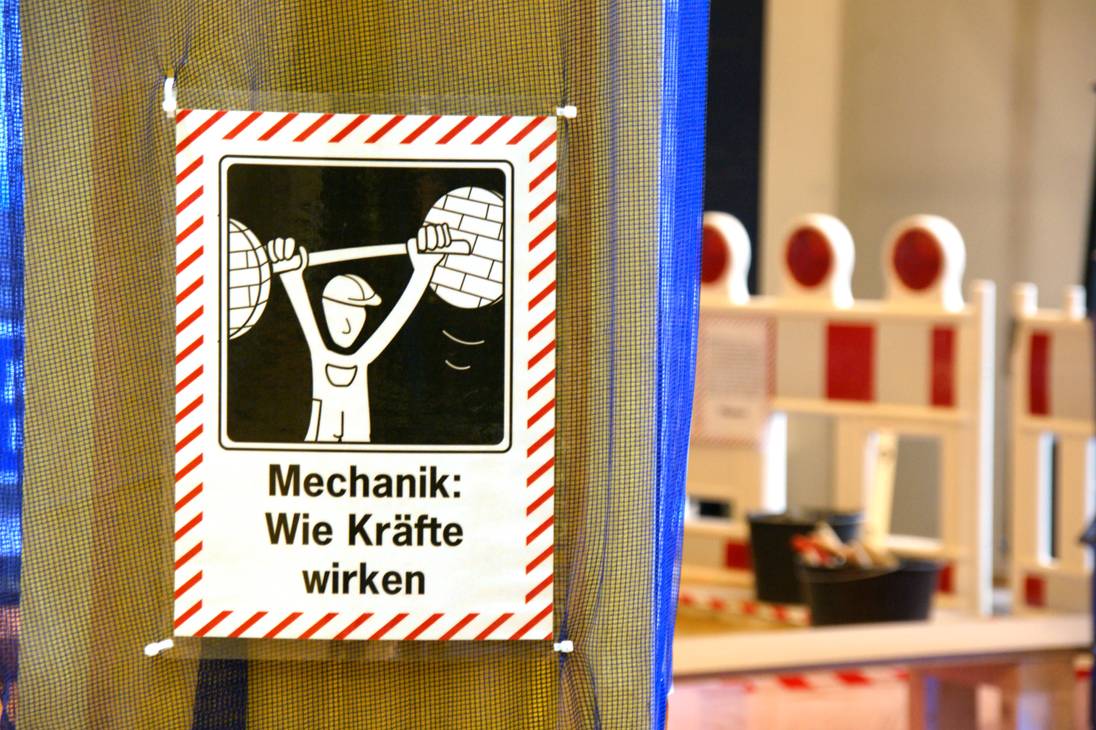 Foto eines Schildes mit einer Grafik von einem Bauarbeiter der ein Gewicht hebt.